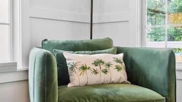 Un sillón verde de terciopelo con un cojín con estampado de palmera.