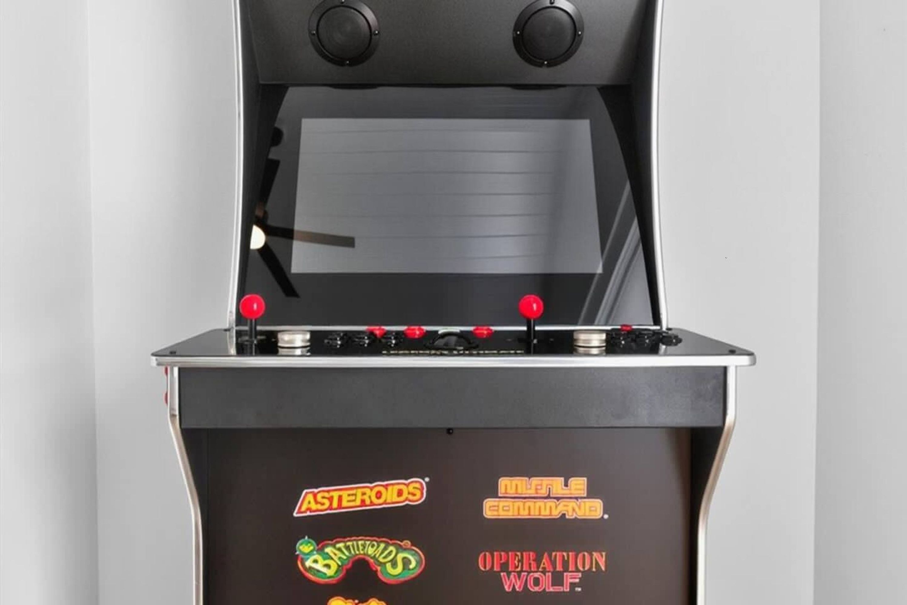 Ein Retro-Arcade-Automat mit Joysticks und Spielbezeichnungen wie Asteroids und BattleGrounds.