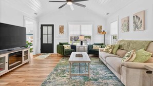 A spacious living room with a ceiling fan, a TV on a cabinet, a sofa, and a coffee table.