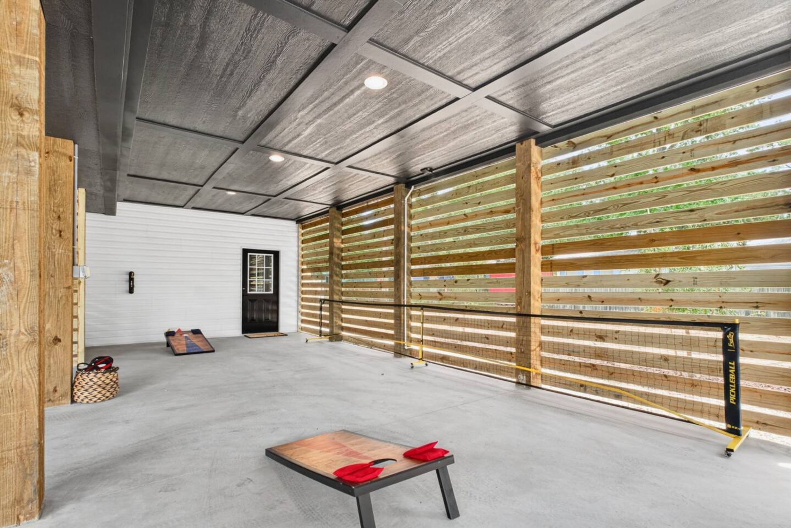 A spacious indoor area with a concrete floor, a wooden bench, and a volleyball net.