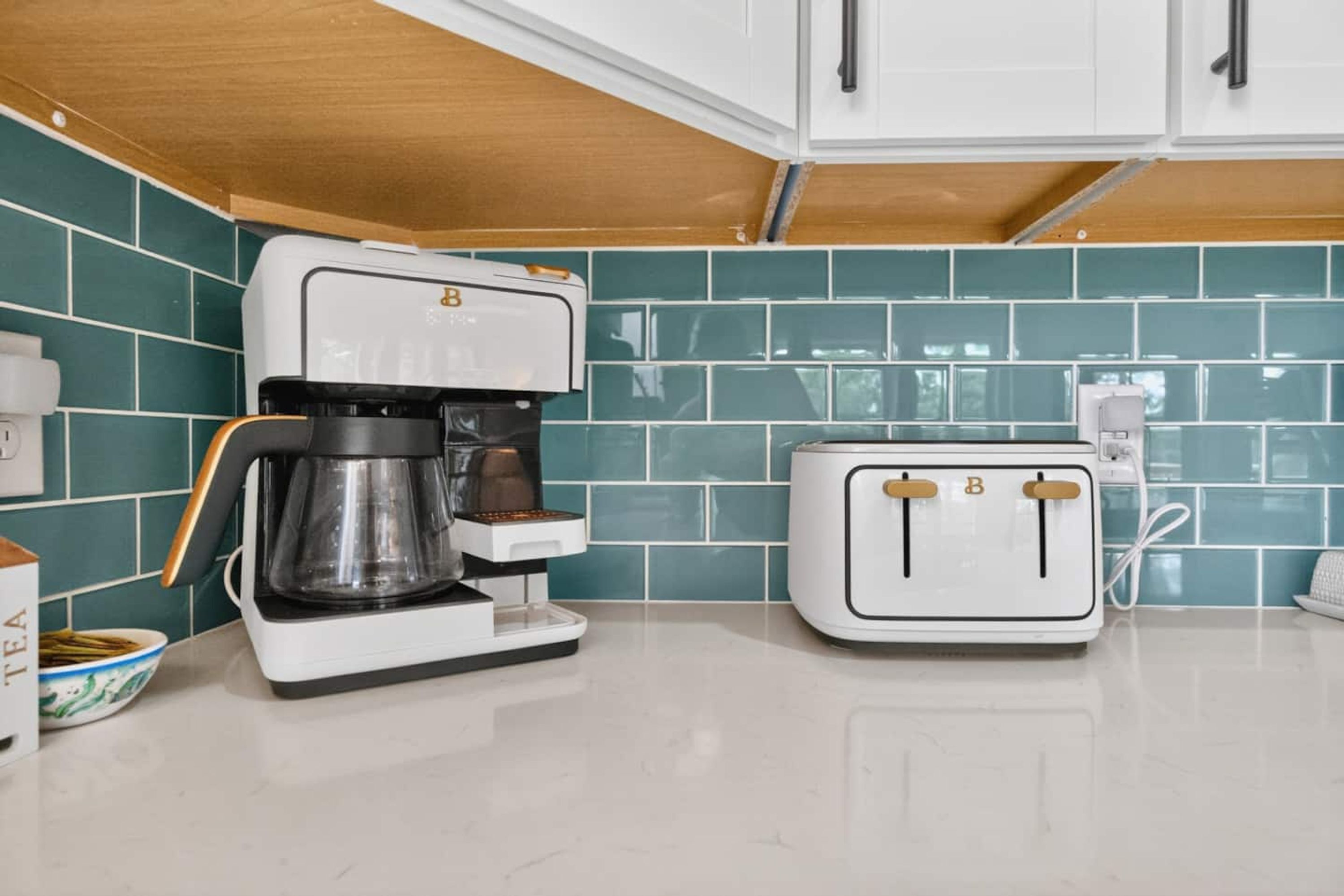 A kitchen with a coffee maker, a toaster, and a bowl of tea leaves.