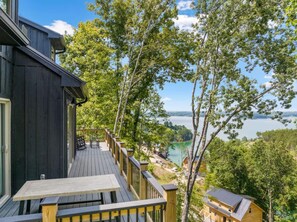 Eine Holterrasse mit Tisch und Stühlen, mit Blick auf einen See und ein bewaldetes Gebiet.
