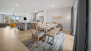 A modern kitchen with white cabinets, a wooden dining table, and a large island. - NEW Luxury Condo Rooftop Terrace EV Charger (Wake Forest)