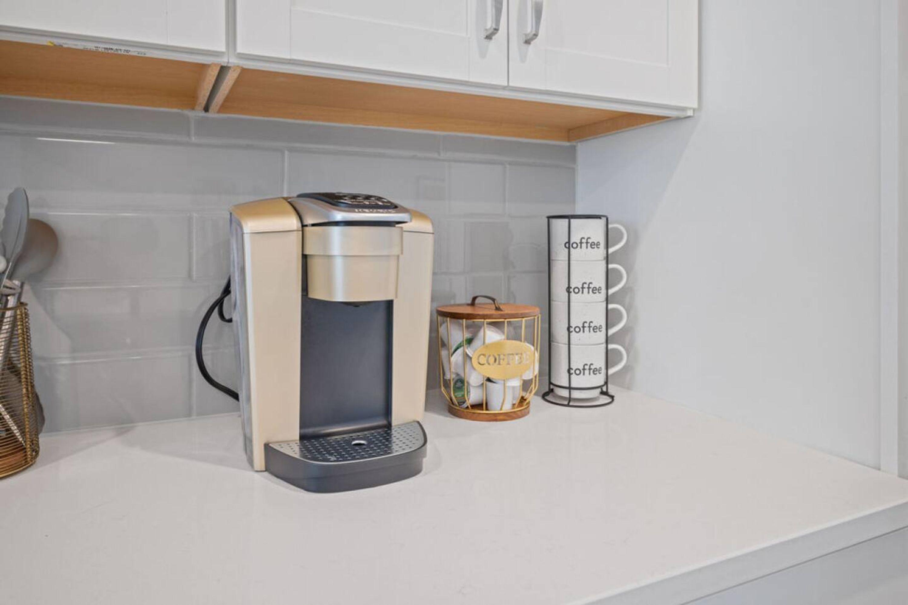A coffee machine on a white countertop with a coffee dispenser and a coffee storage container with the word 'coffee' on it.
