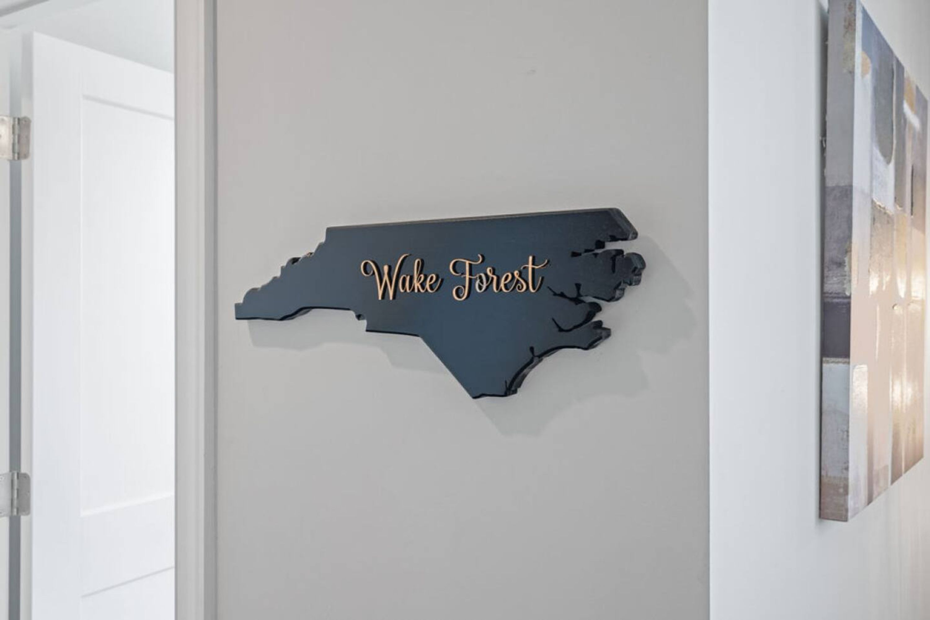 Eine an der Wand hängende Karte von North Carolina mit dem Schriftzug "Wake Forest" in goldener Schrift.