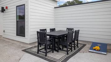 Un patio con una mesa y sillas negras, un tapete y una alfombra azul con un lazo amarillo.
