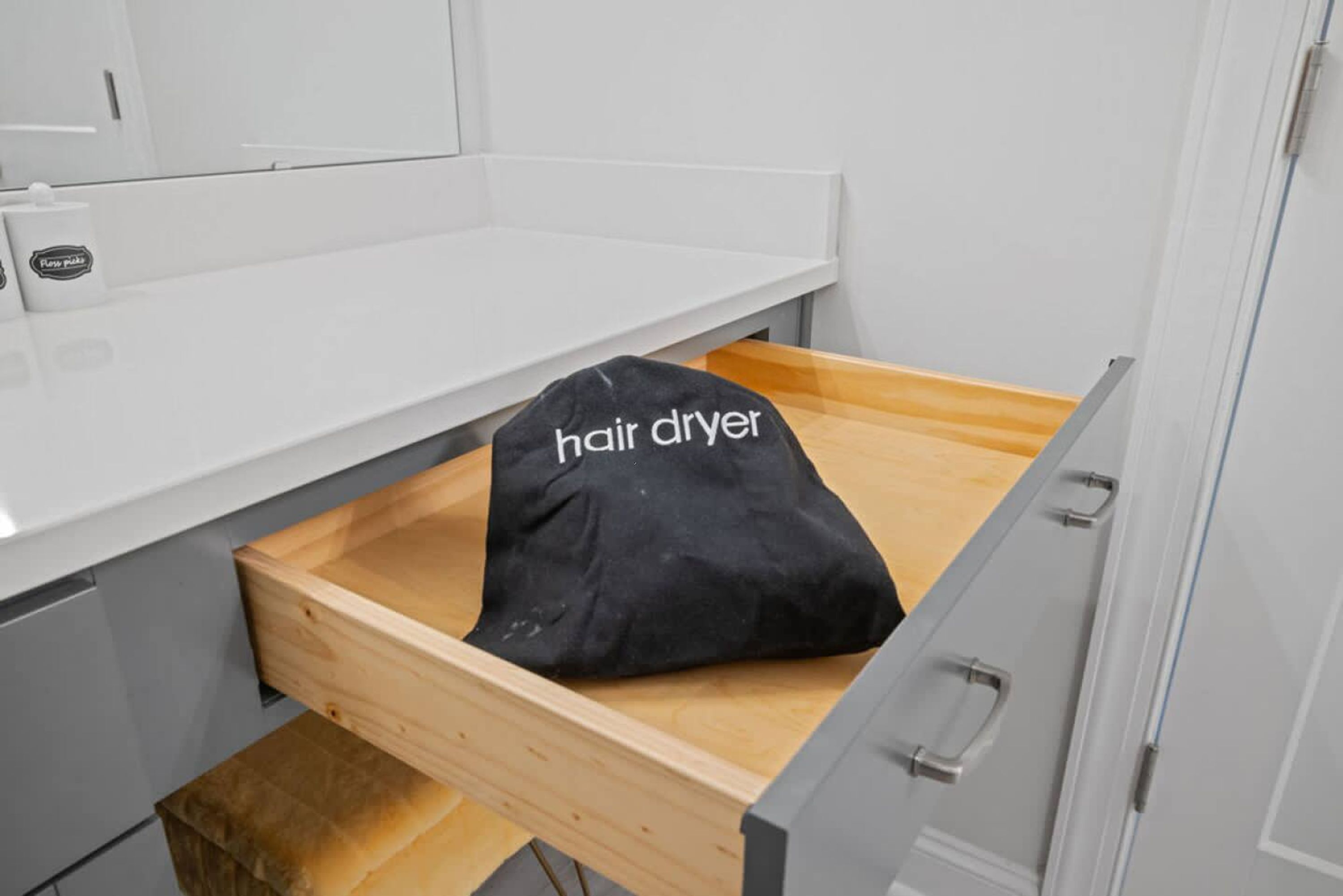 Un cajón de madera con una bolsa negra que lleva la etiqueta 'secador de pelo' en su interior.