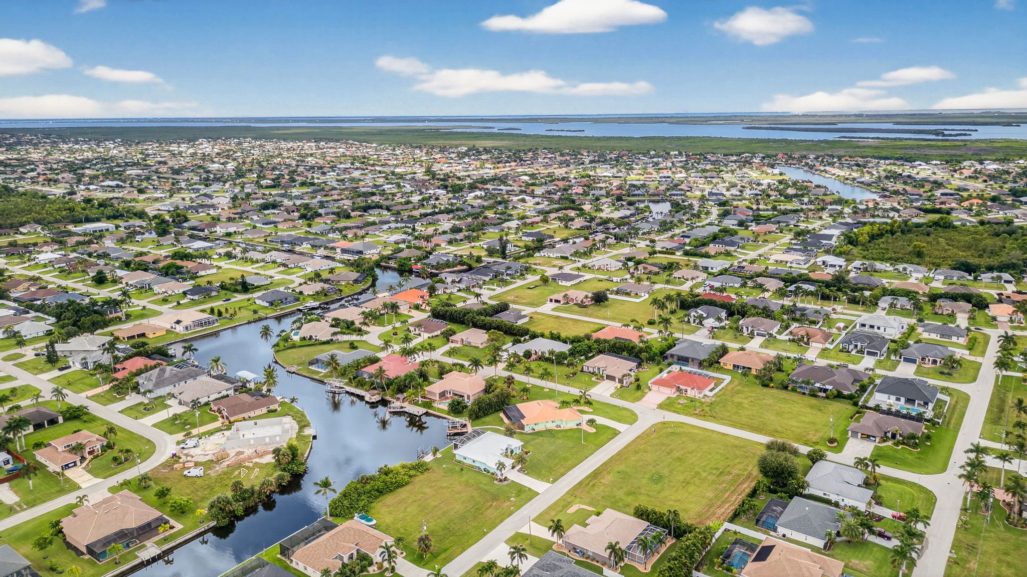 Una zona residencial con casas, un canal y una masa de agua distante.