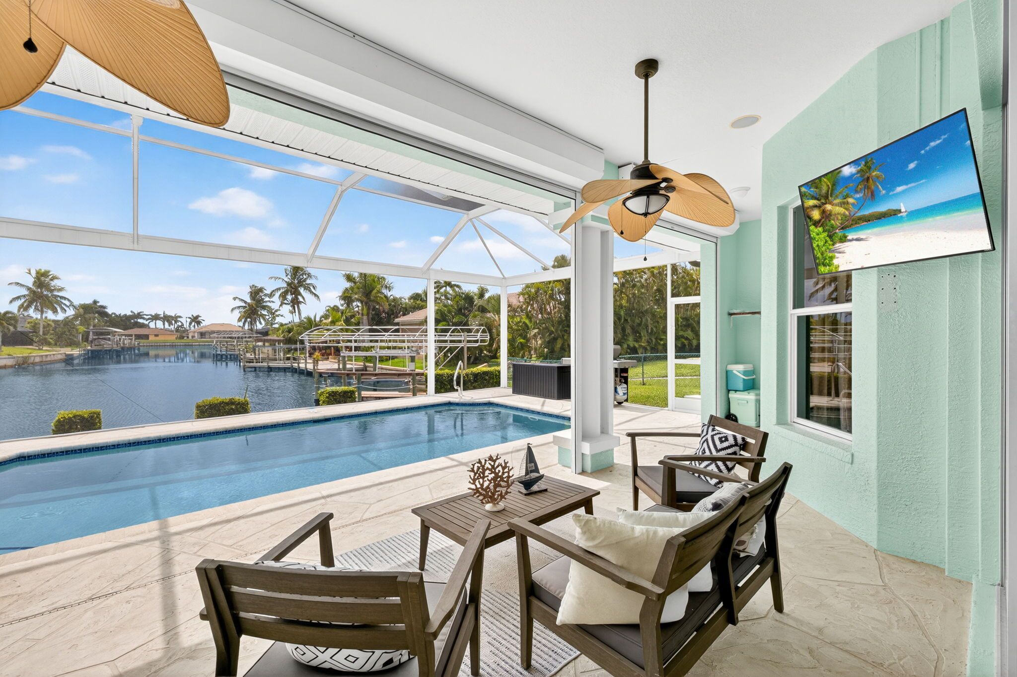 A poolside area with a view of a lake, wooden furniture, and a ceiling fan.
