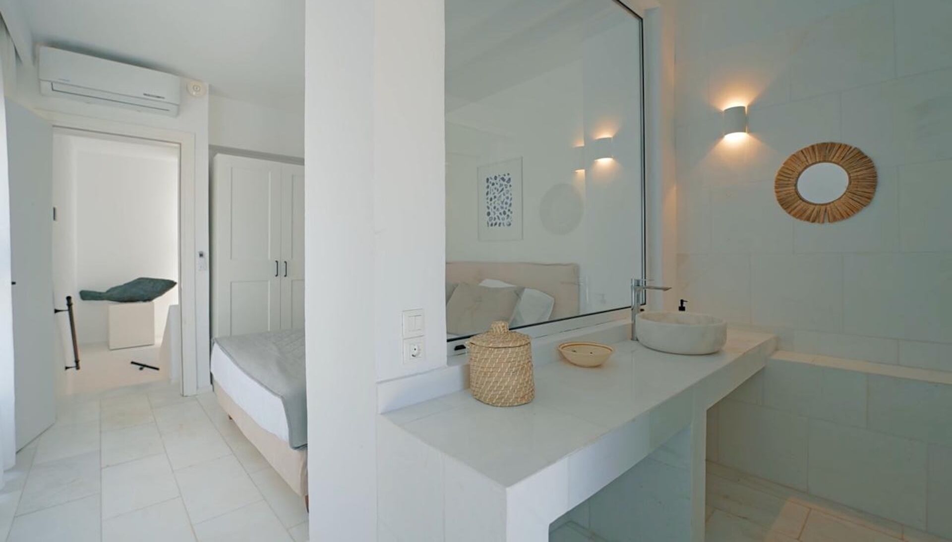 A modern bathroom with a large mirror, a round wall decoration, and a white sink.