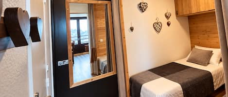 Un dormitorio con cama, espejo, armarios de madera y adornos con forma de corazón en la pared.