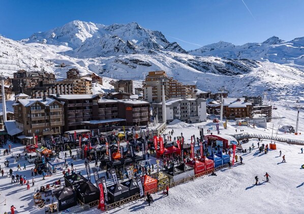 A snow-covered mountain town with buildings, tents, and people. - Apartment 'Higginson Val Thorens' with Mountain View and Balcony (Les Belleville)