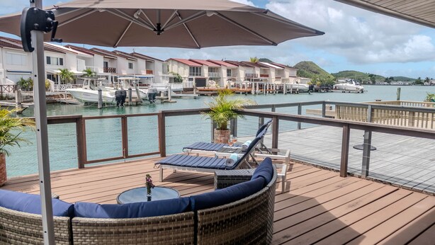 A deck with wicker furniture, a table with a vase, and an umbrella.
