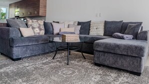 A modern living room with a sectional sofa, a coffee table, and a patterned rug.