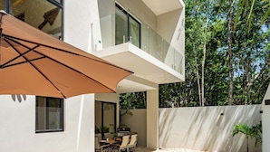 Una casa moderna con piscina, terraza de madera y mobiliario exterior.