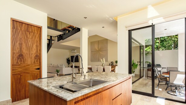 Una cocina moderna con encimera de granito, armarios de madera e instalación de lavamanos.