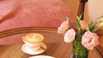 Ein Glastisch mit einem Teller Essen, einer Kaffeetasse und einer Vase mit Blumen.