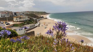 A coastal beach with a promenade, beach umbrellas, and a clear view of the sea. - Ribeiro House (Lourinhã)