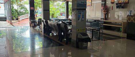 A spacious lobby with a glass partition, seating area, and a reception desk.