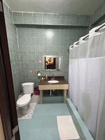 A bathroom with a toilet, sink, mirror, and shower curtain.