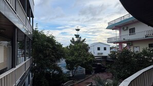 A multi-story building with balconies, a courtyard with a small water feature, and a clear sky. - Chinatown hotel (Caye Caulker)