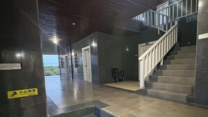 A staircase leading to an upper level with a handrail and a sign indicating a wet floor. - Chinatown hotel (Caye Caulker)