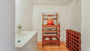 A white tiled bathroom with a wooden shelf holding plates and a vase with flowers. - Vacation Home 'La Casita Cueva Don Carmelo' with Mountain View, Private Terrace & Wi-Fi (San Bartolomé de Tirajana)