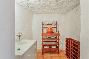A white tiled bathroom with a wooden shelf holding plates and a vase with flowers. - Vacation Home 'La Casita Cueva Don Carmelo' with Mountain View, Private Terrace and Wi-Fi (San Bartolomé de Tirajana)
