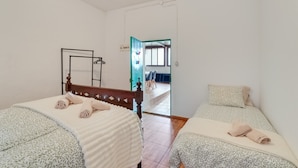 A room with two beds, a mirror, and a view of a dining area. - Vacation Home 'La Casita Cueva Don Carmelo' with Mountain View, Private Terrace & Wi-Fi (San Bartolomé de Tirajana)