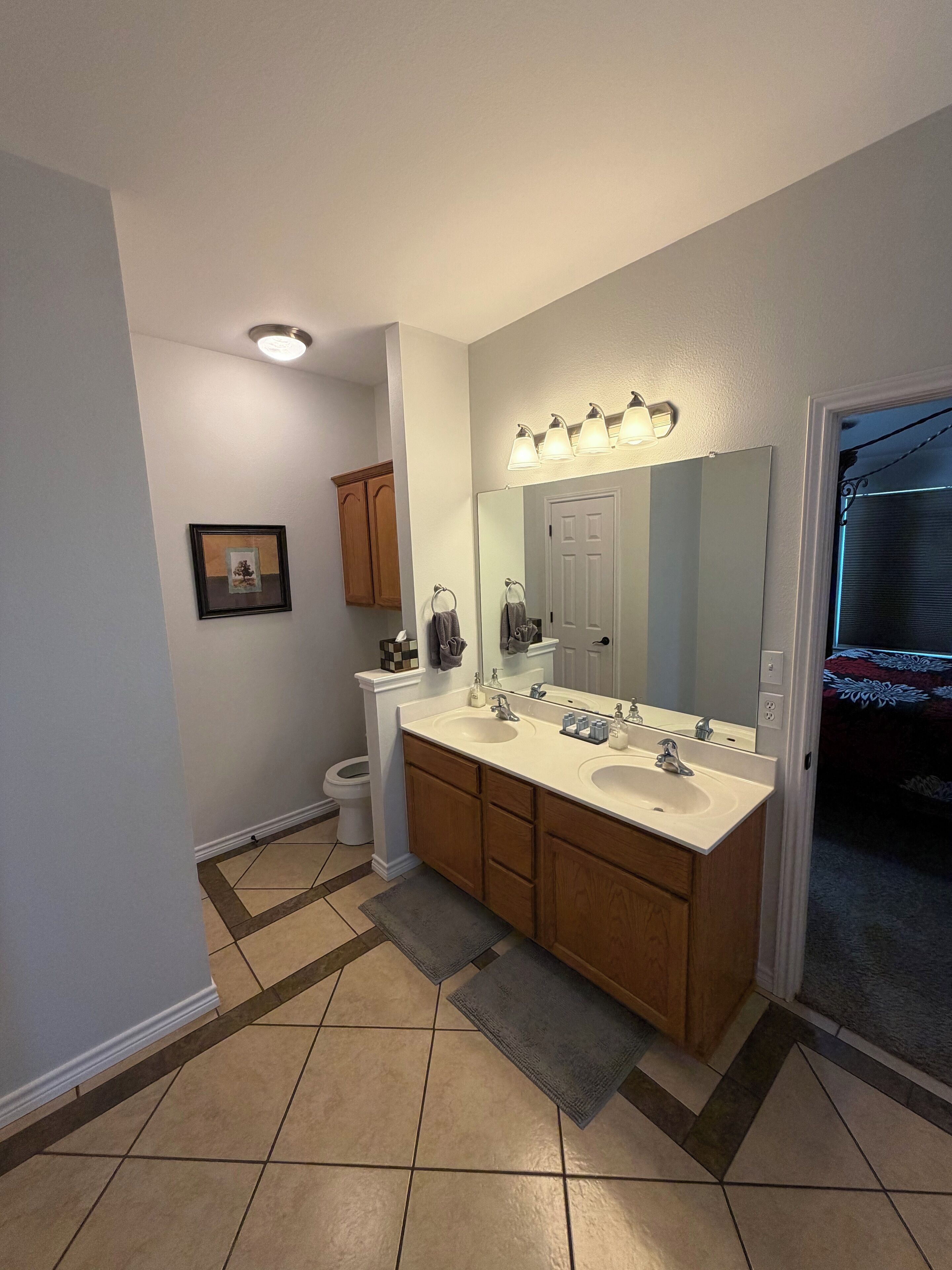 A bathroom with a double sink vanity, a large mirror, and a light fixture above the mirror.