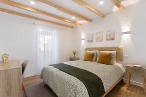 A bedroom with a bed, bedside table, lamp, and a window with curtains.