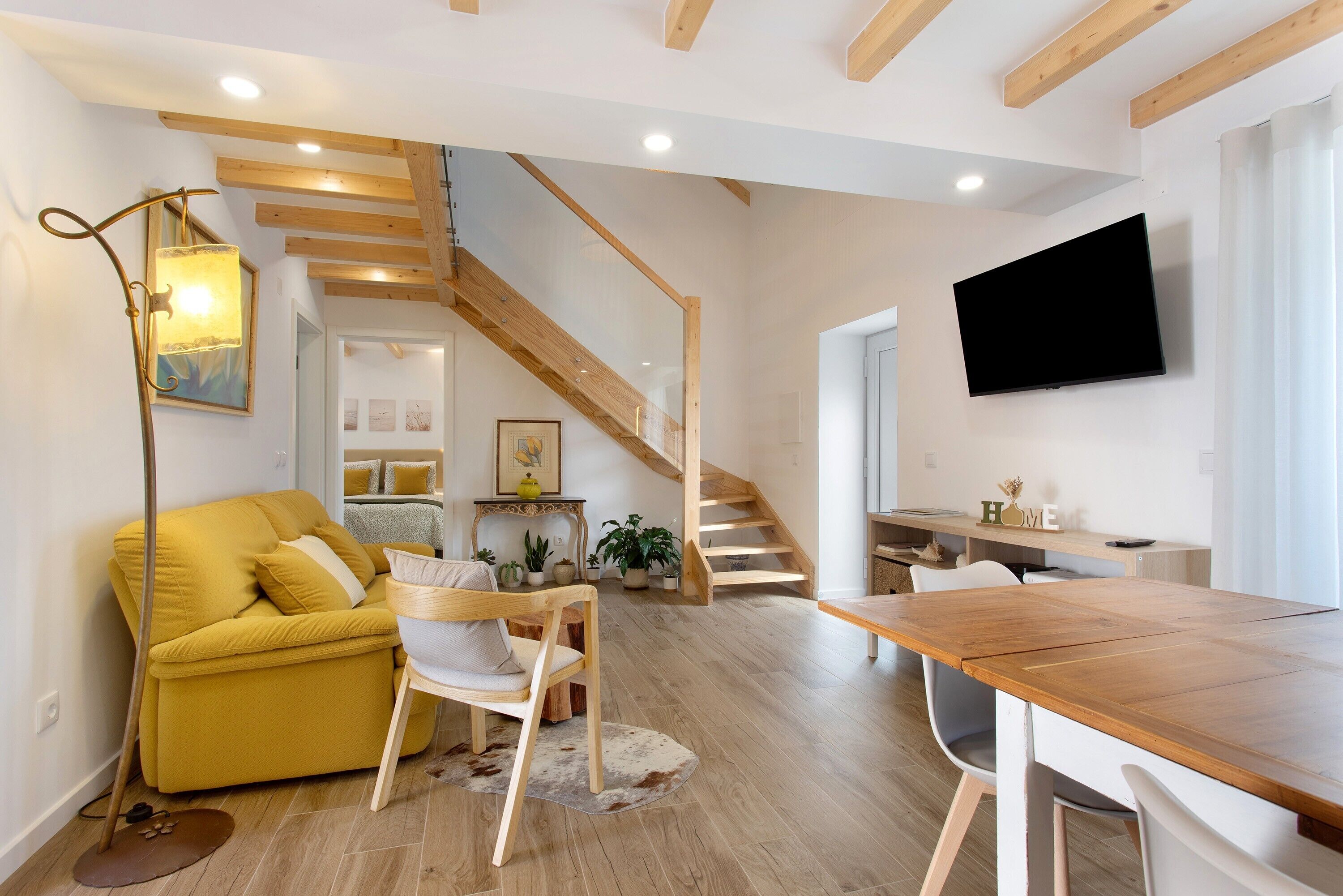 Una sala de estar moderna con sofá, mesa de comedor de madera y una escalera.