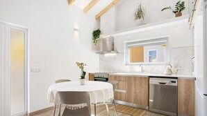 A modern kitchen with wooden cabinets, a stainless steel dishwasher, and a window above the sink. - Zeca Holidays Atalaia Mezzanine Apartment with Balcony and Wi-Fi (Atalaia)