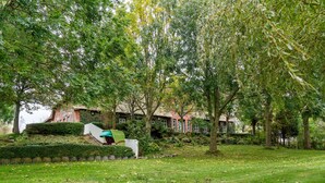 A park with a grassy area, trees, and a building with a red roof. - Apartment 'Ferienwohnung Süd-West' with Private Garden and Wi-Fi (Pellworm)