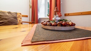 A wooden dining table with a woven placemat, a bowl of chestnuts, and a ceramic fox figurine. - Apartment 'Ferienwohnung Süd-West' with Private Garden and Wi-Fi (Pellworm)