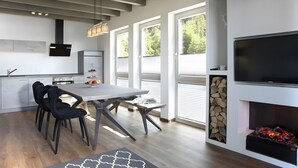 A modern kitchen with a dining area, large windows, and a fireplace. - Apartment 'Atemlos' with Spa Area and Mountain View (Ibach)