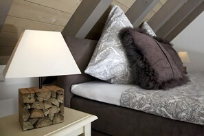 A modern living room with a sofa, patterned cushions, a lamp, and a stack of logs as a side table.
