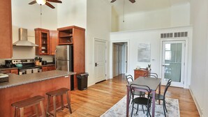 A spacious kitchen with wooden cabinets, a stainless steel refrigerator, and a bar area with stools. - Lookout Loft over the Monroe Square (Monroe)