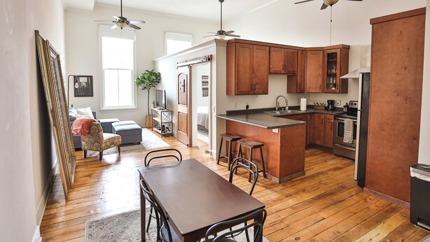 A spacious kitchen with wooden cabinets, a central island, and a dining area with a table and chairs. - Lookout Loft over the Monroe Square (Monroe)