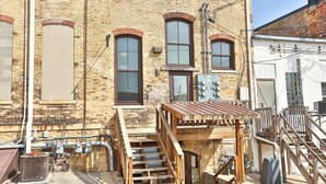 A brick building with multiple windows, a wooden staircase, and outdoor electrical equipment. - Lookout Loft over the Monroe Square (Monroe)