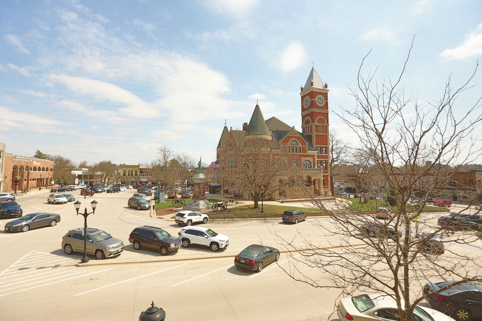 A parking lot with cars and a historic building with a clock tower in the background.