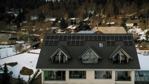 A modern house with a sloped roof, solar panels, and multiple windows. - Apartment 'Halali' with Spa Area and Mountain View (Ibach)