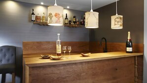 A bar area with wooden counter, hanging pendant lights, and shelves with bottles. - Apartment 'Kuckucks' with Spa Area and Mountain View (Ibach)