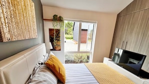 Een slaapkamer met een bed, een televisie en een raam.