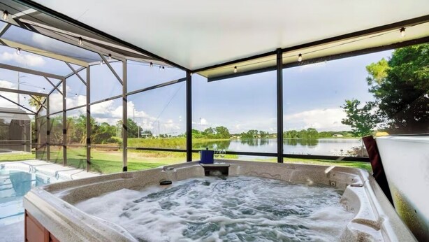 A hot tub with a view of a lake and greenery.