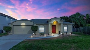A single-story house with a red door, a garage, and a well-maintained lawn.