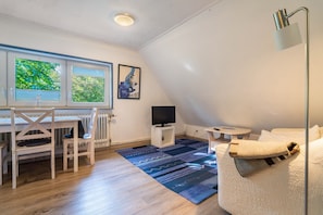 Une pièce comprenant une table à manger, des chaises, un téléviseur, un canapé et un tapis à motifs.