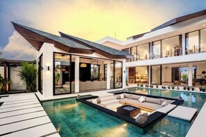 Ein modernes Haus mit großem Pool, Sitzgelegenheiten im Freien und großen Fenstern.
