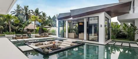 A modern house with a swimming pool, outdoor seating, and tropical vegetation.