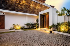 A modern building with a paved courtyard, wooden slatted walls, and potted plants. - Villa Baia by BaliSuperHost (Bali)